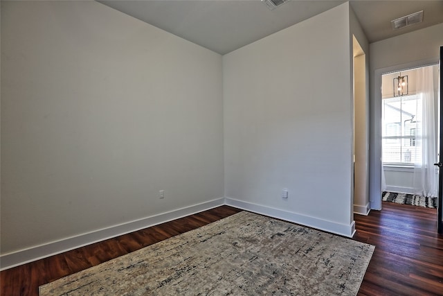 unfurnished room with dark wood finished floors, visible vents, and baseboards