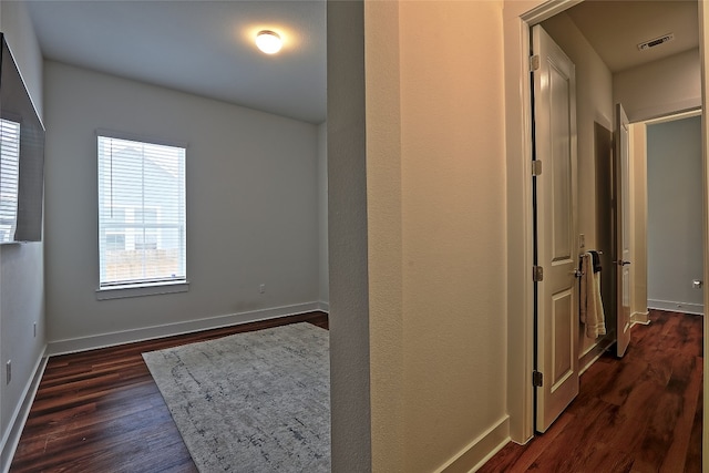 hallway featuring visible vents, baseboards, and dark wood finished floors