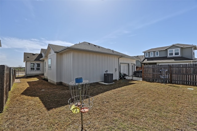 view of side of home featuring board and batten siding, a lawn, cooling unit, a garage, and a fenced backyard