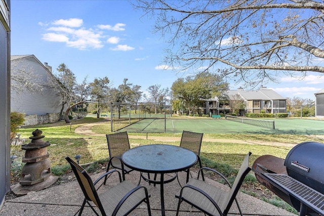 view of patio / terrace featuring a tennis court, fence, and a grill