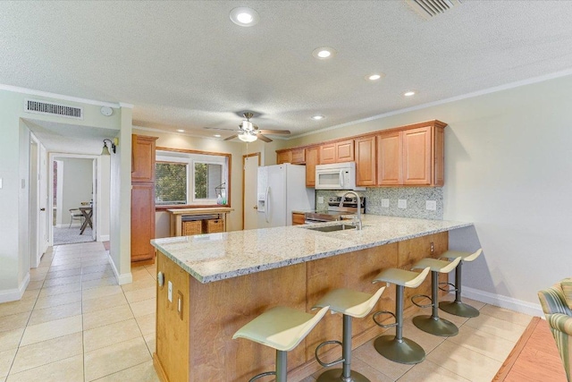 kitchen with white appliances, visible vents, a peninsula, a sink, and tasteful backsplash