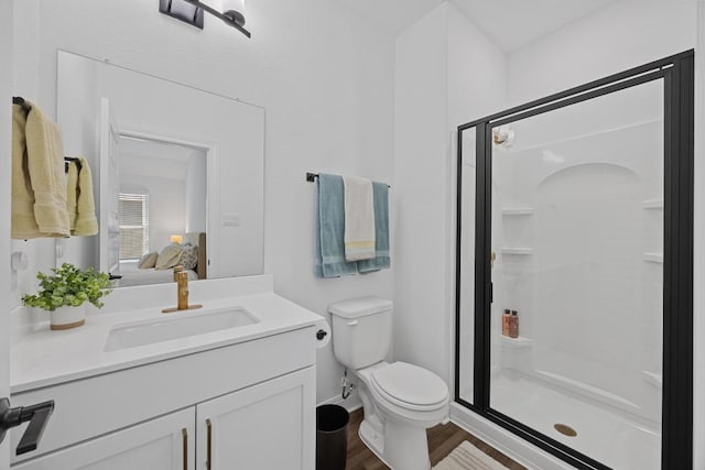 ensuite bathroom with vanity, wood finished floors, a shower stall, toilet, and connected bathroom