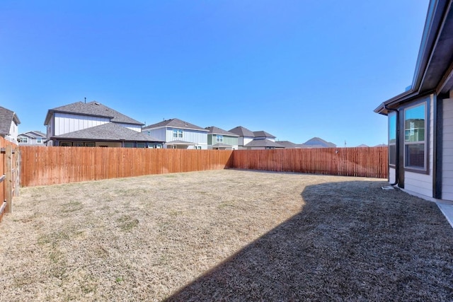 view of yard featuring a fenced backyard and a residential view