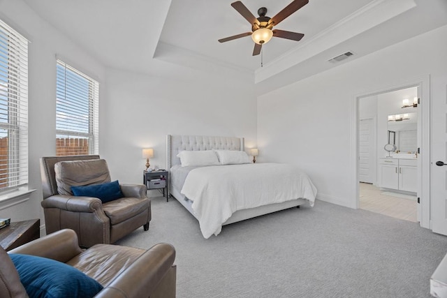 bedroom featuring visible vents, ensuite bathroom, light carpet, a raised ceiling, and ceiling fan with notable chandelier