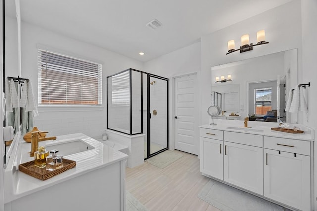 bathroom featuring visible vents, a shower stall, a garden tub, recessed lighting, and vanity