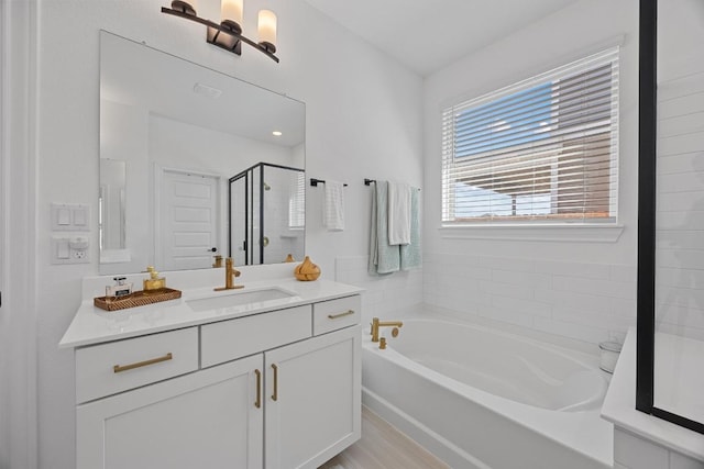 bathroom featuring vanity, a shower stall, and a garden tub