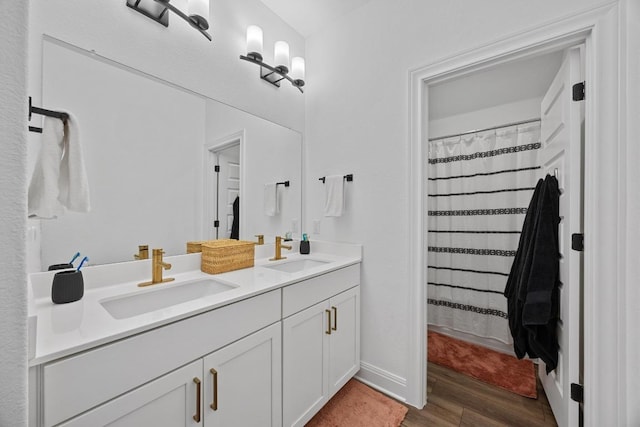 bathroom with curtained shower, double vanity, wood finished floors, and a sink