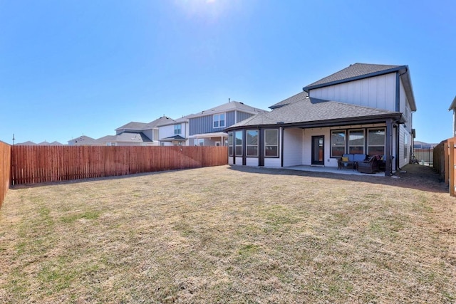 rear view of property with a patio, a lawn, a fenced backyard, and a shingled roof