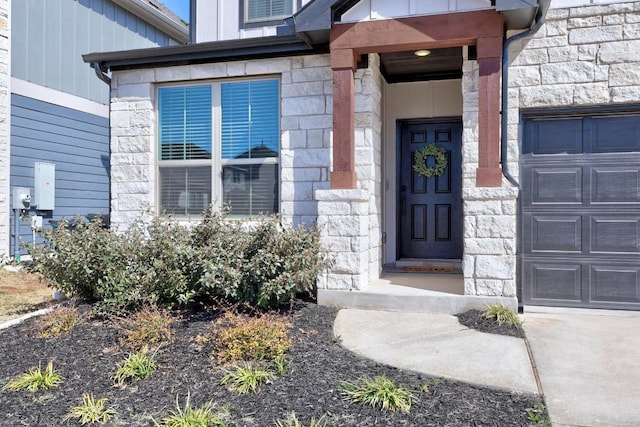 entrance to property with a garage, stone siding, and board and batten siding