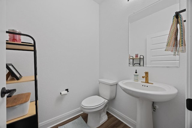 bathroom featuring a sink, baseboards, toilet, and wood finished floors