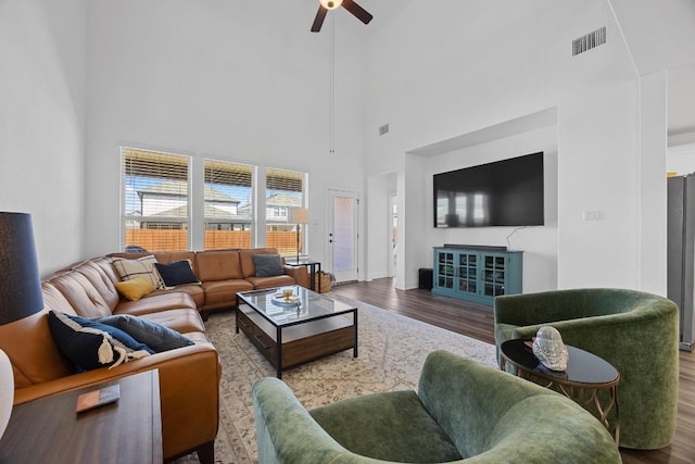 living area with visible vents, baseboards, wood finished floors, and a ceiling fan