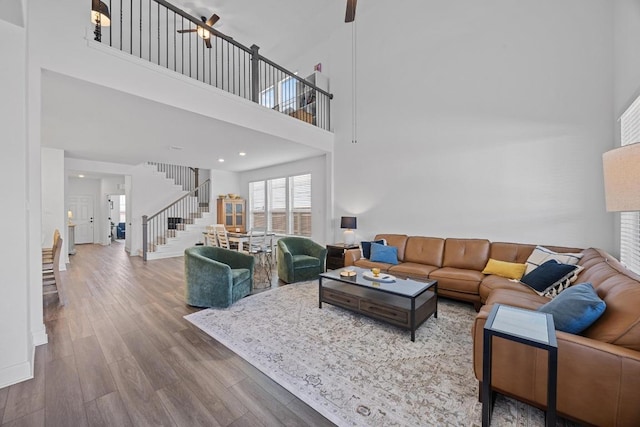 living room with stairs, recessed lighting, a high ceiling, wood finished floors, and a ceiling fan