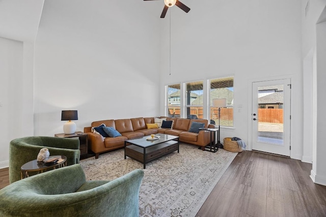 living room with a towering ceiling, baseboards, dark wood-style floors, and a ceiling fan