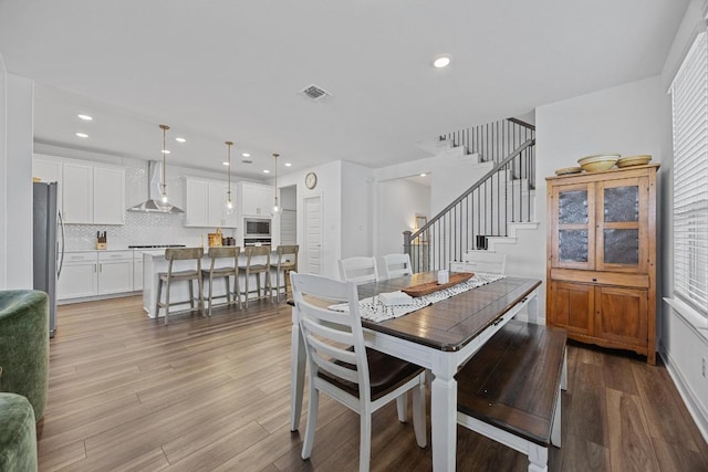 dining space featuring visible vents, recessed lighting, stairs, and wood finished floors