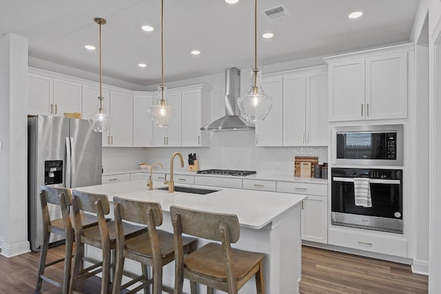 kitchen featuring a sink, stainless steel appliances, dark wood-style floors, and wall chimney range hood