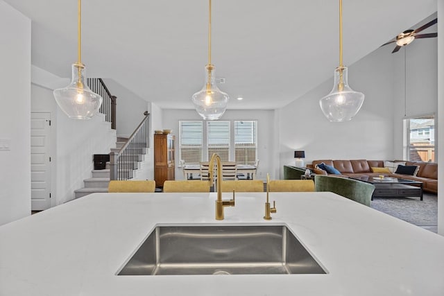 kitchen featuring a sink, decorative light fixtures, open floor plan, and a ceiling fan