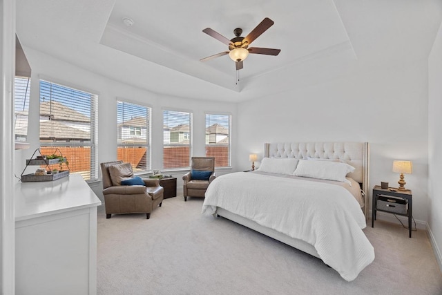 bedroom with light colored carpet, baseboards, a raised ceiling, and ceiling fan