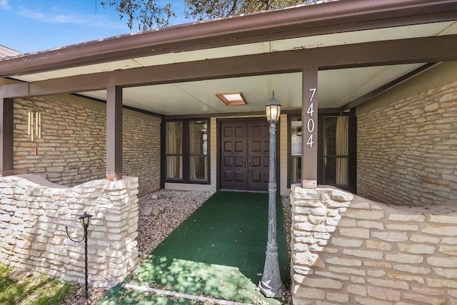 entrance to property featuring stone siding and a porch