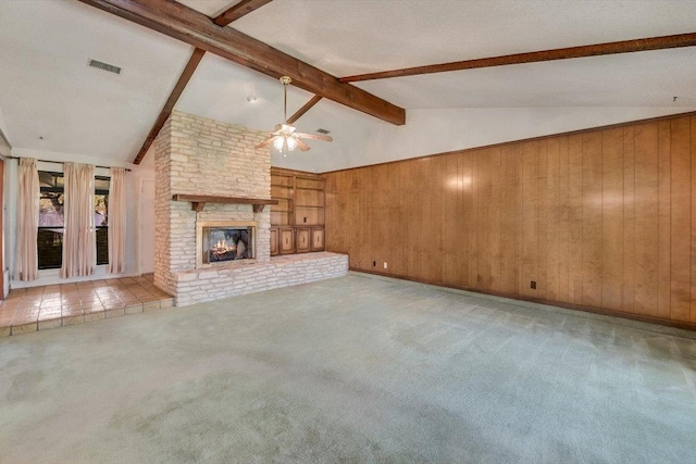 unfurnished living room with wooden walls, visible vents, vaulted ceiling with beams, ceiling fan, and carpet flooring