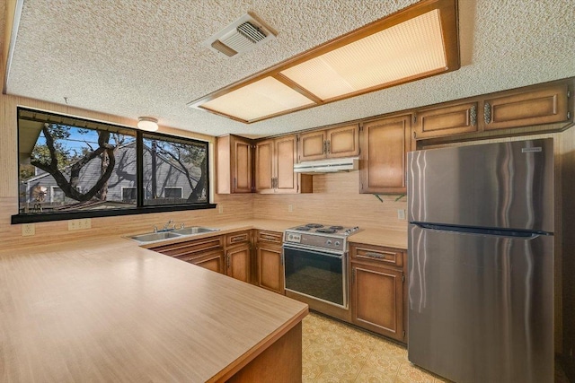 kitchen with a sink, brown cabinets, under cabinet range hood, and stainless steel appliances