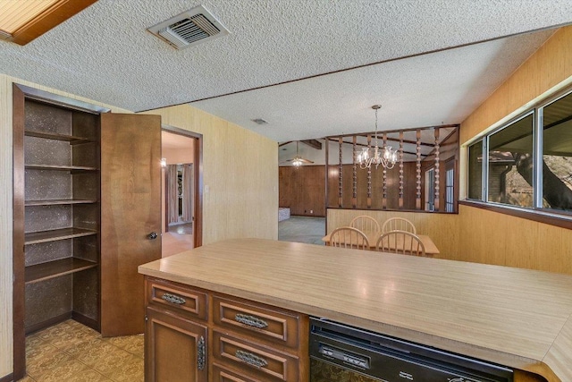 kitchen featuring visible vents, a textured ceiling, an inviting chandelier, wood walls, and dishwasher