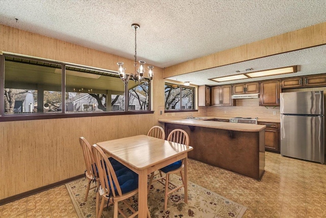 dining area with a notable chandelier, light floors, wood walls, and a textured ceiling