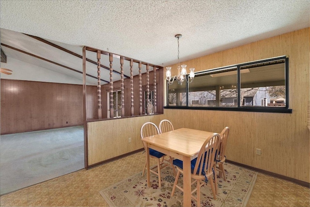 dining space featuring tile patterned floors, lofted ceiling, a notable chandelier, and wooden walls