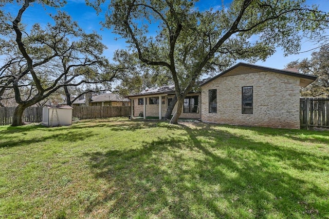 view of yard featuring an outbuilding, a fenced backyard, and a shed