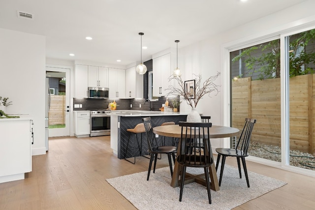 dining area featuring visible vents, a healthy amount of sunlight, and light wood finished floors