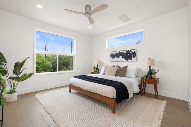 bedroom with wood finished floors, multiple windows, baseboards, and visible vents