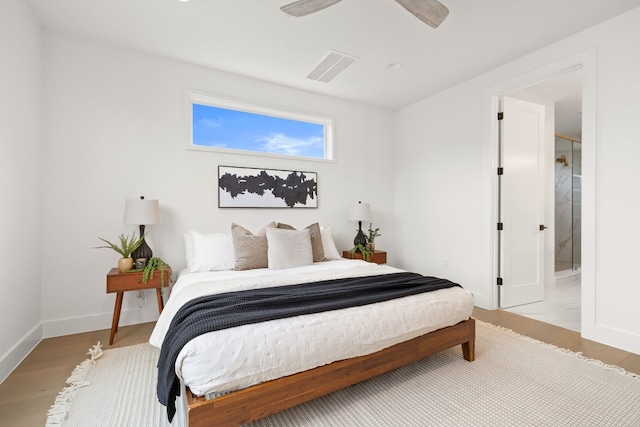 bedroom with visible vents, baseboards, wood finished floors, ensuite bath, and a ceiling fan