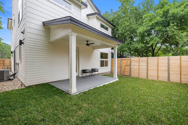 back of property with a lawn, a ceiling fan, a patio, a fenced backyard, and central AC unit