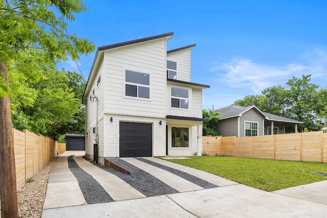 modern home with concrete driveway, fence, and a front yard