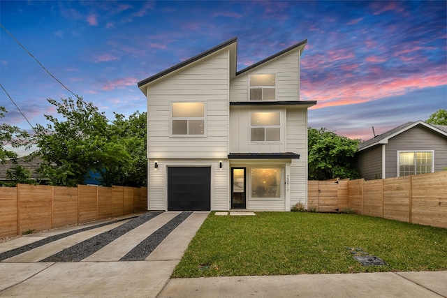 modern home with concrete driveway, fence, a garage, and a lawn