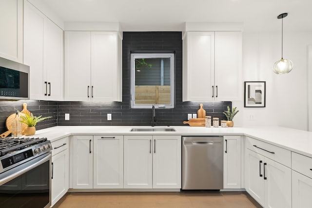 kitchen featuring a sink, decorative backsplash, appliances with stainless steel finishes, and white cabinets