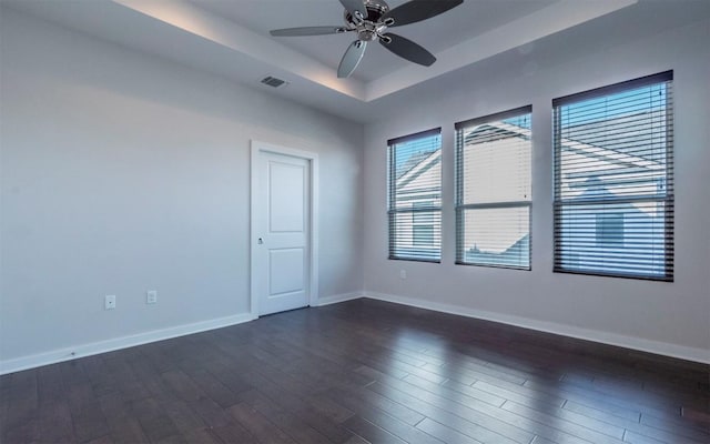 unfurnished room with dark wood-style floors, a ceiling fan, a raised ceiling, and baseboards