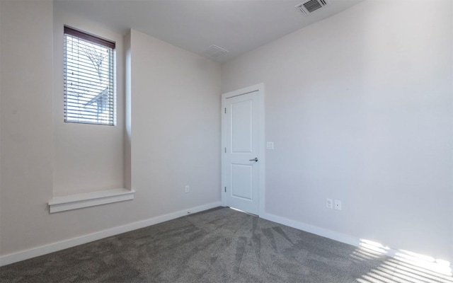 empty room with visible vents, baseboards, and dark colored carpet