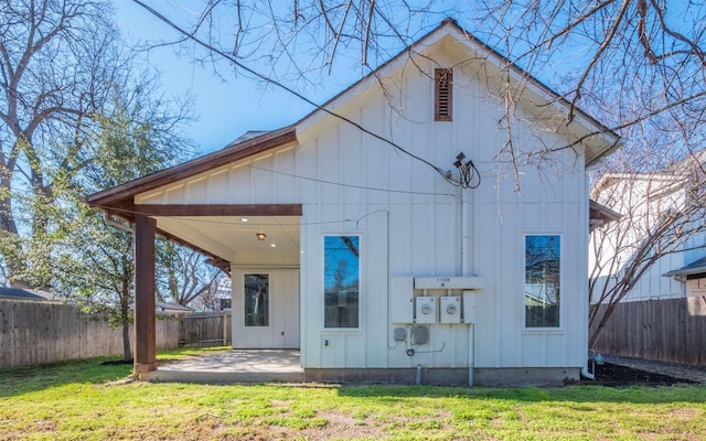 back of house featuring a patio, a lawn, board and batten siding, and a fenced backyard