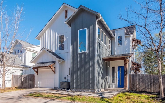 view of front of property featuring an attached garage, fence, board and batten siding, and central AC