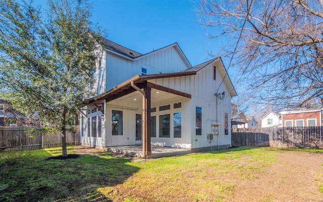 back of property with a fenced backyard, a patio, a yard, and board and batten siding