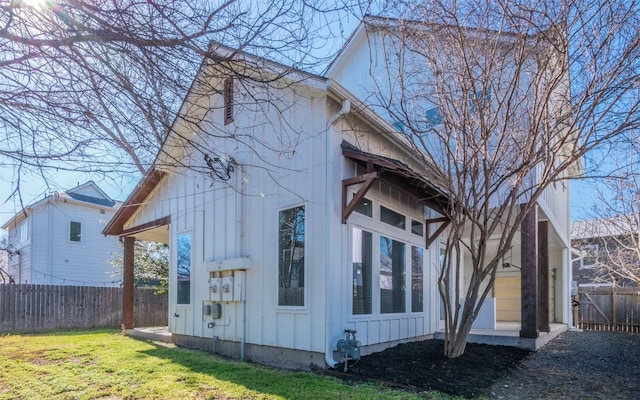 view of property exterior featuring board and batten siding, fence private yard, and a yard