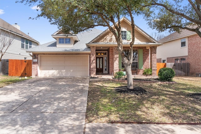 view of front of house with brick siding, driveway, an attached garage, and fence