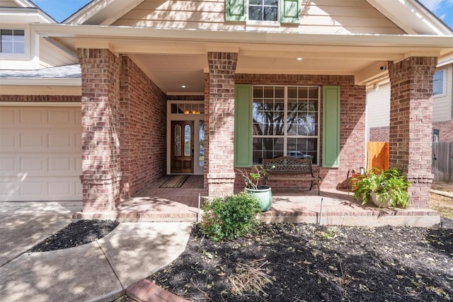 entrance to property featuring brick siding, covered porch, and an attached garage