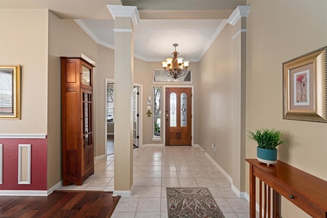 foyer entrance with an inviting chandelier, light tile patterned floors, baseboards, and ornamental molding