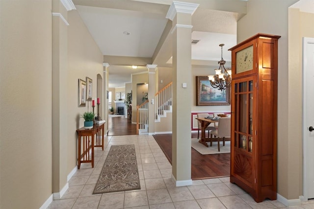 entryway featuring visible vents, a notable chandelier, light tile patterned floors, stairs, and ornate columns