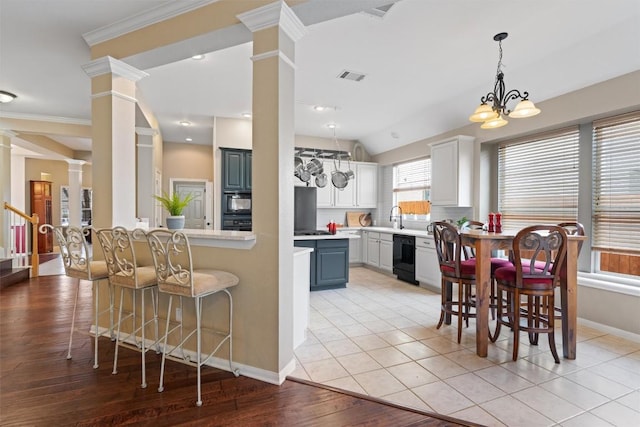 kitchen with a breakfast bar area, ornate columns, a sink, light countertops, and a chandelier