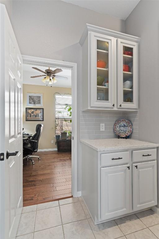 bar with light tile patterned floors, backsplash, baseboards, and a ceiling fan