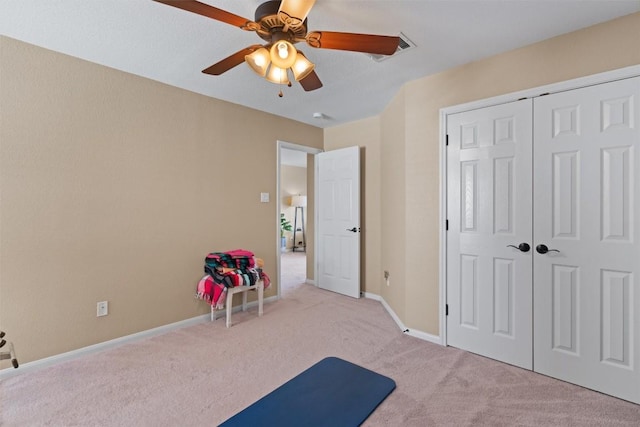 exercise area with baseboards, a ceiling fan, and carpet floors