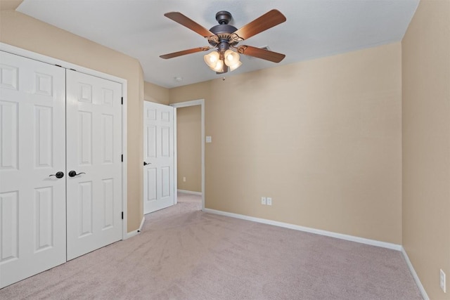 unfurnished bedroom with a closet, baseboards, light colored carpet, and a ceiling fan