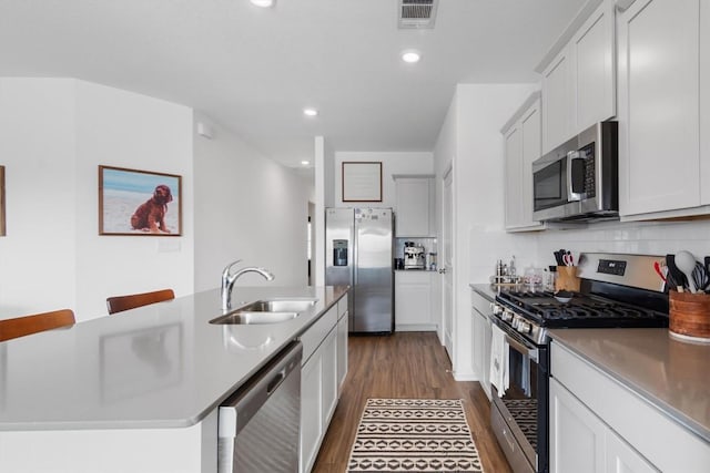 kitchen featuring visible vents, dark wood finished floors, a sink, decorative backsplash, and stainless steel appliances